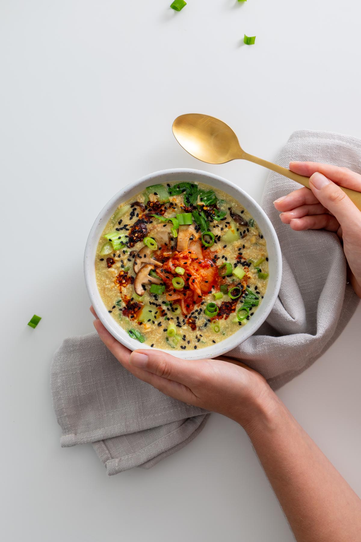 Sarah Cobacho holding a bowl of savory vegan oats topped with kimchi and greens
